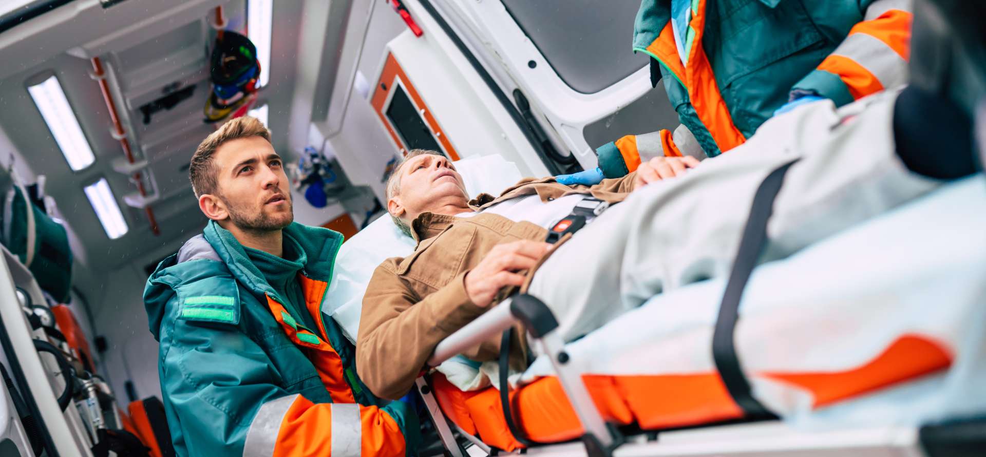 Emergency responders assisting an injured person beside an ambulance equipped with an onboard computer for reliable fleet connectivity